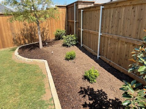 Stone-edged mulch beds along the fence